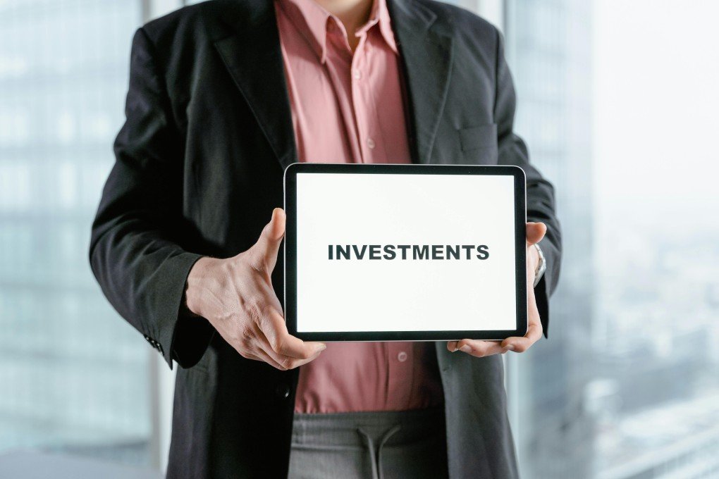 Businessman holding a tablet with the word "INVESTMENTS" – myfastbroker stock brokers
