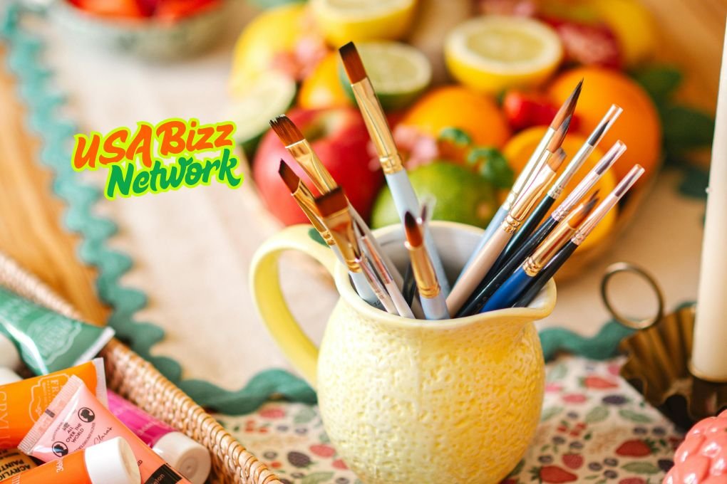 Art brushes in a yellow cup with colorful fruits in the background – Artofzio creative workspace