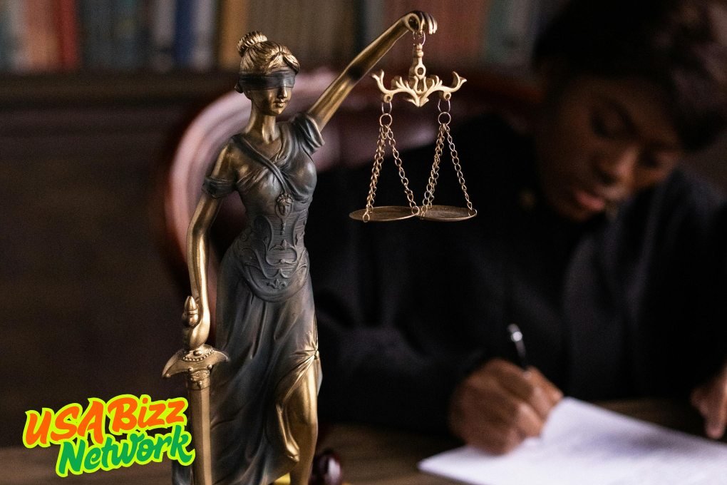 Lady Justice with Legal Professional – Rockford Mesothelioma Lawyer Vimeo Blindfolded Lady Justice statue with legal professional in background — rockford mesothelioma lawyer vimeo, USA Bizz Network branding.